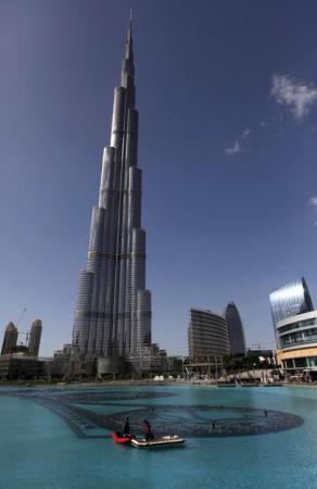 Workers move on a boat in an artificial lake at Dubai Mall in front of the Burj Khalifa.