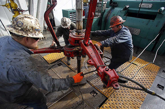 Roughnecks wrestle pipe on a True Company oil drilling rig outside Watford, North Dakota, United States.