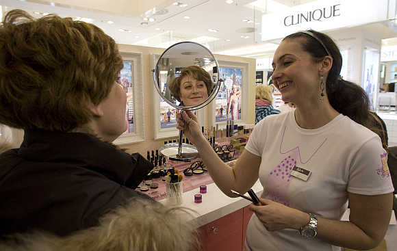 A beautician holds up a mirror to a customer after applying her with make-up at the KaDeWe department store in Berlin, Germany.