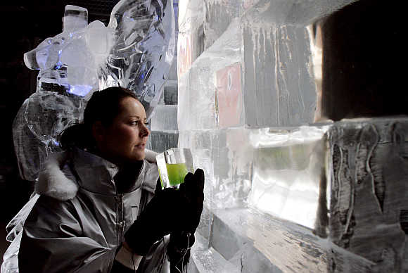 Party guest Trisha Wilson drinks a cocktail and views an ice sculpture at the launch of London's first ice bar.