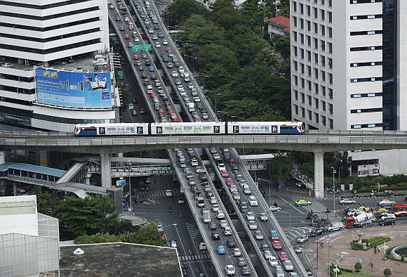A skytrain passes over vehicles on the road during rush hour in Bangkok.