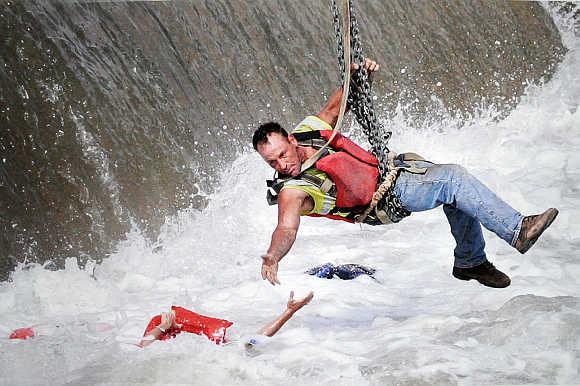 A construction worker, suspended from a crane, rescues a woman who fell into the Des Moines River near the Center Street Dam in Des Moines, Iowa.