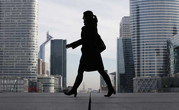 A businesswoman is silhouetted as she makes her way under the Arche de la Defense, in the financial district west of Paris, France.
