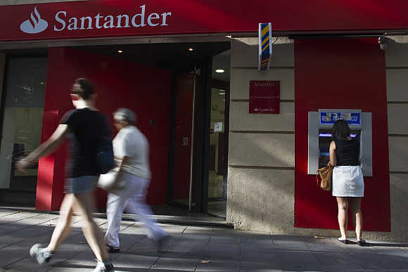 A woman uses an ATM machine at a Santander bank branch in Madrid, Spain.