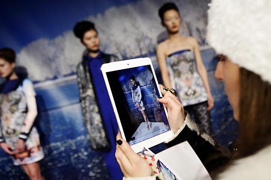 A woman takes a photo of models using an Apple iPad.