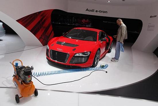 A worker for German car manufacturer Audi stands next to an R8 Audi e-tron.