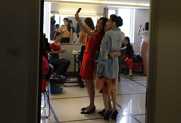 Contestants take a picture of themselves with a mobile phone backstage before the recording of a TV show in Beijing.