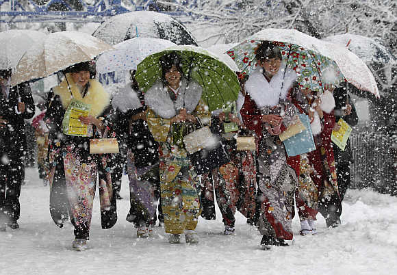 Women in kimonos walk to attend a ceremony celebrating Coming of Age Day in heavy snowfall at Toshimaen amusement park in Tokyo.