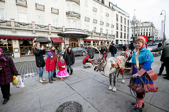 A Laplander woman wearing traditional costume stands with a reindeer outside the Grand Hotel in Oslo.