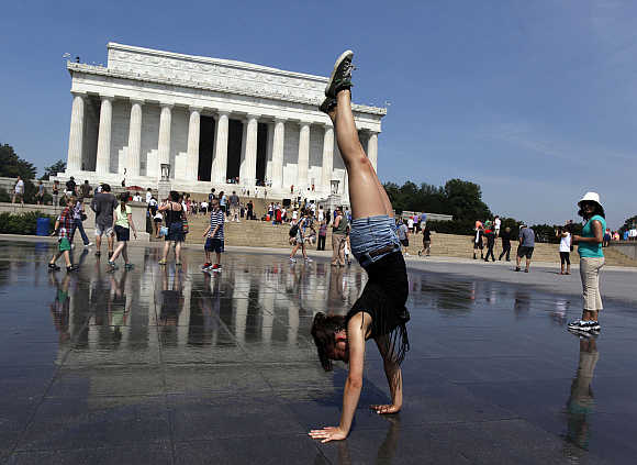Sabrina Hatch of Idaho practices her handstand underneath sprinklers at the Lincoln Memorial in Washington, DC.