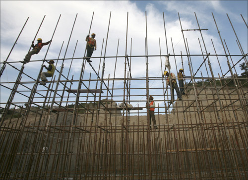 Workers fasten iron rods together at the construction site of a bridge on the outskirts of Jammu.
