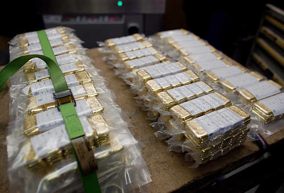 Vacuum-packed gold bars of 100 grams are placed on a table.