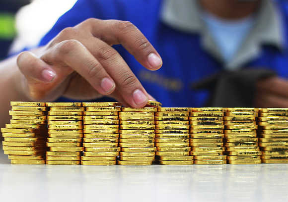 An employee holds a gold piece, each weighing 100 grams, at the state-owned mining company PT Antam Tbk metal refinery in Jakarta, Indonesia.