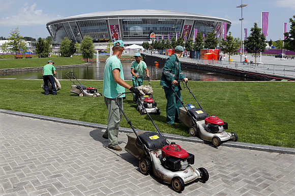 Workers cut the grass around the Donbass Arena stadium in Donetsk, Ukraine.