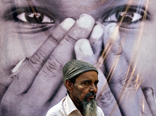 A survivor stands in front of a poster during a photo-exhibition held to commemorate the 10th anniversary of Godhra riots.