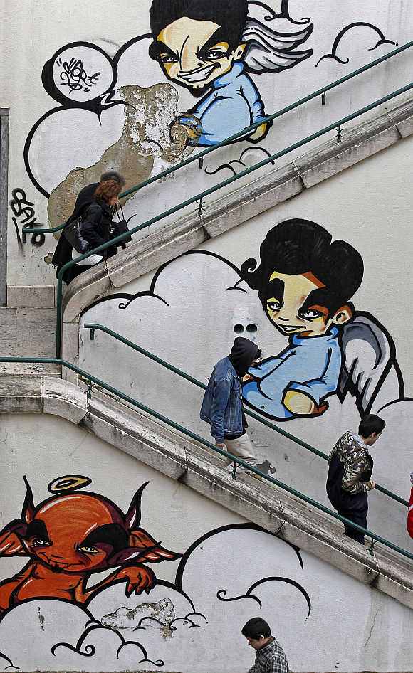 People walk past a staircase on a street in Lisbon, Portugal.