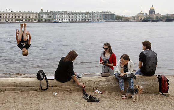People enjoy a warm day on the banks of the Neva River in central St Petersburg, Russia.