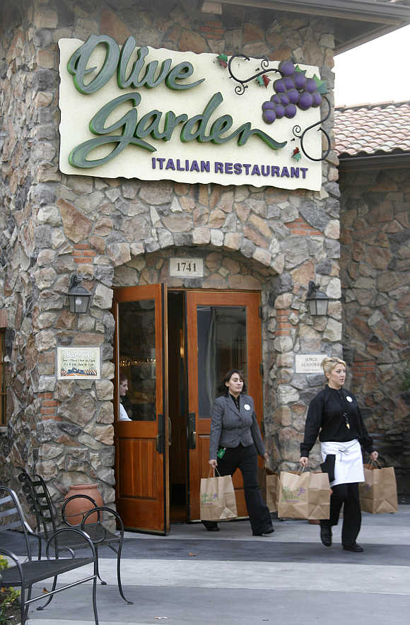 An Olive Garden employee helps a customer carry an order of food to her car at an Olive Garden restaurant in Burbank, California, United States.