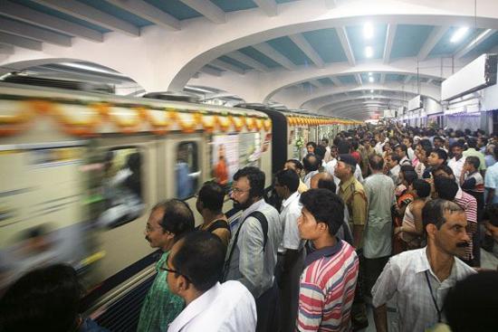 Passengers stand on a platform at a metro station.