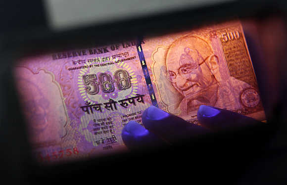 An employee checks a currency note at a cash counter inside a bank in Mumbai.