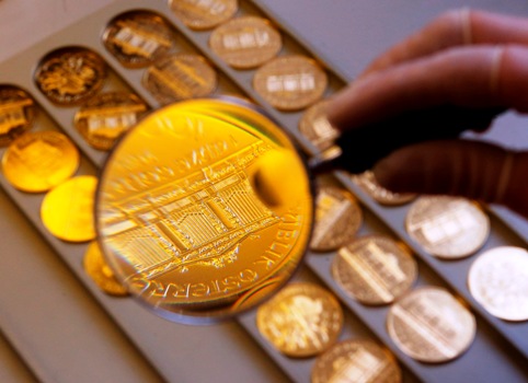 A worker at the Austrian Mint checks a gold Vienna Philharmonic bullion coin for defects in the company's headquarters in Vienna.