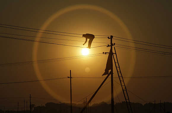 An employee works on overhead power cables in Allahabad.