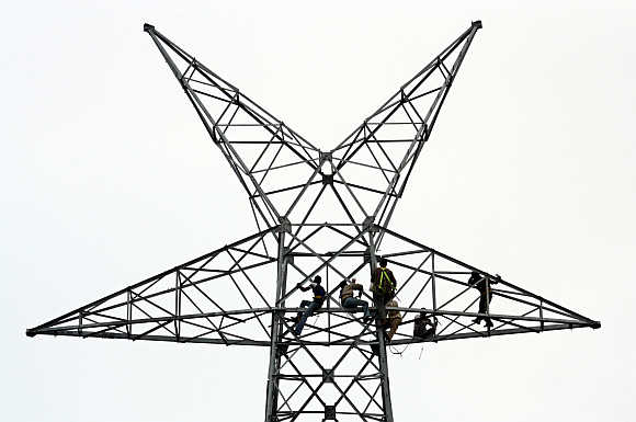 Workers install cables on electric pylon in Ahmedabad.