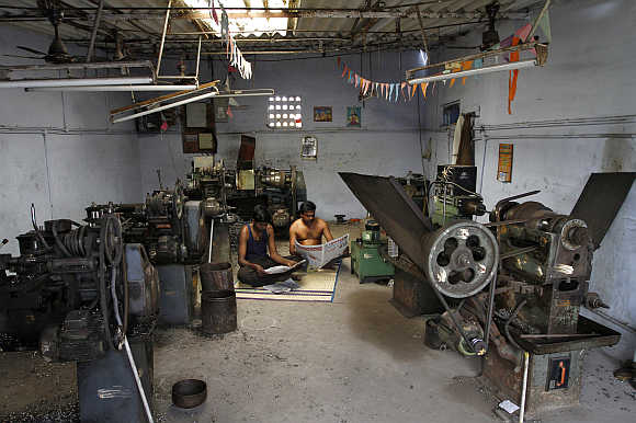Workers at a small scale factory read newspapers during a power cut in Coimbatore.