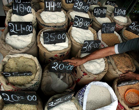 A shopkeeper arranges signs with prices on bags of rice at a shop in Mumbai.