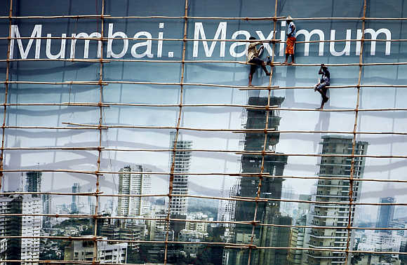 Labourers work on a billboard in Mumbai.