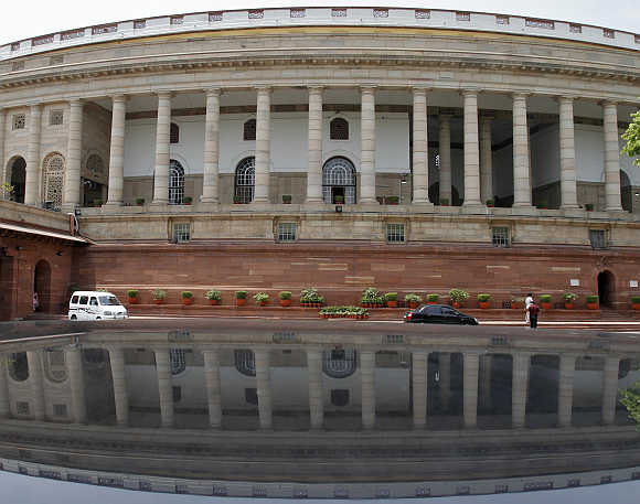 Parliament building is reflected on a car in New Delhi.