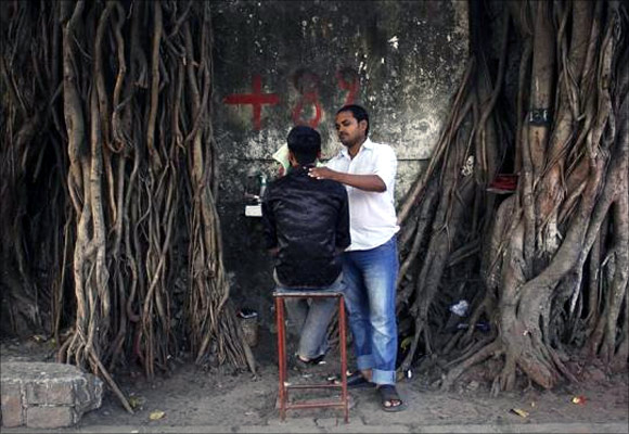 A man gets a shave by a roadside barber in a slum area in Mumbai.