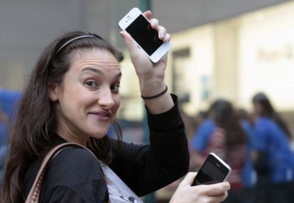A customer shows off her new iPhone 4S as she leaves an Apple Store in New York.
