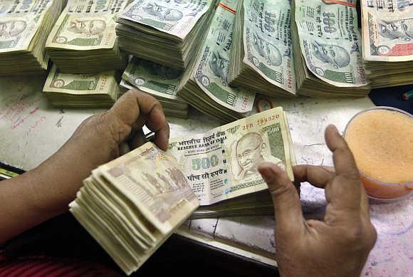 An employee counts rupee notes at a cash counter inside a bank in Kolkata.