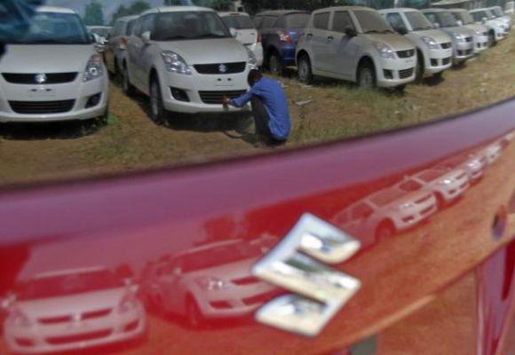 A worker cleans a Maruti Suzuki Swift Dzire car as he is being reflected on a car at the company's stock yard at Sanand, Gujarat.