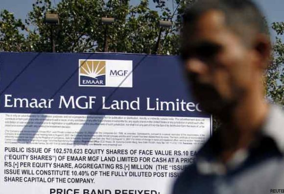 A man walks past a billboard displaying Initial Public Offering details for Emaar MGF Land.