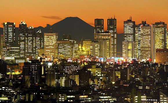Skyscrapers in Tokyo's Shinjuku district frame Mt Fuji at dusk.