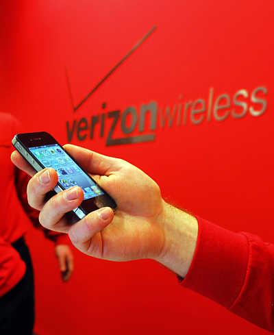 An employee holds out an iPhone for a customer at a Verizon store in Boston, Massachusetts.