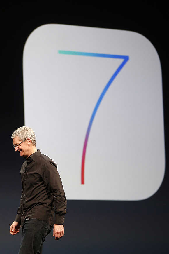 Apple CEO Tim Cook walks past an iOS 7 logo during the Apple Worldwide Developers Conference 2013 in San Francisco, California.