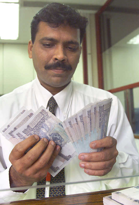 A bank employee counts hundred rupee notes in Mumbai.