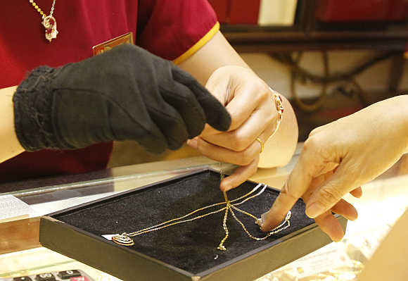 An employee, left, shows gold products to a client at a shop in Hanoi, Vietnam.