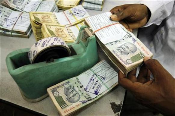 An employee arranges currency notes at a cash counter inside a bank in Agartala.