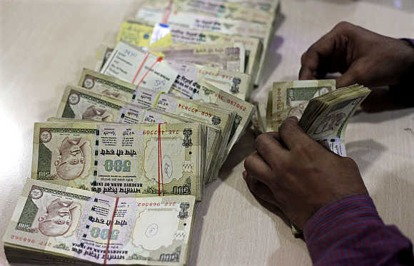 An employee counts rupee notes at a cash counter inside a bank in Mumbai.