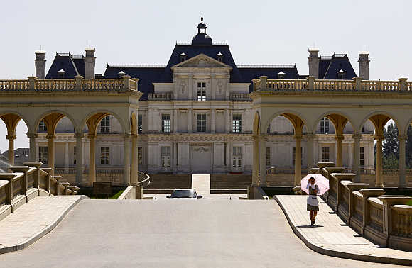A waitress carrying an umbrella walks down the driveway to Chateau Laffitte Hotel, an imitation of the 1650 Chateau Maisons-Laffitte by French architect Francois Mansart, located on the outskirts of Beijing.