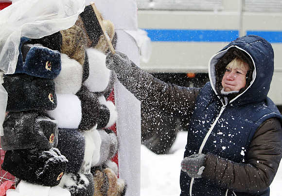 A shop assistant removes snow from Russian traditional hats, also known as Ushanka hats, near Red Square during heavy snowfall in central Moscow.
