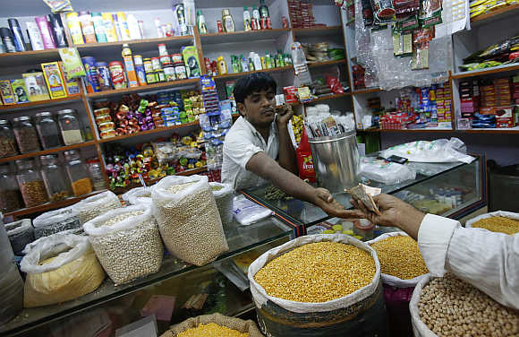 The owner of a Kirana, or mom-and-pop grocery store, accepts money from a customer in Mumbai.