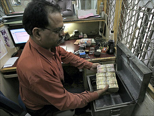 An employee arranges Indian currency notes at a cash counter inside a bank in New Delhi.