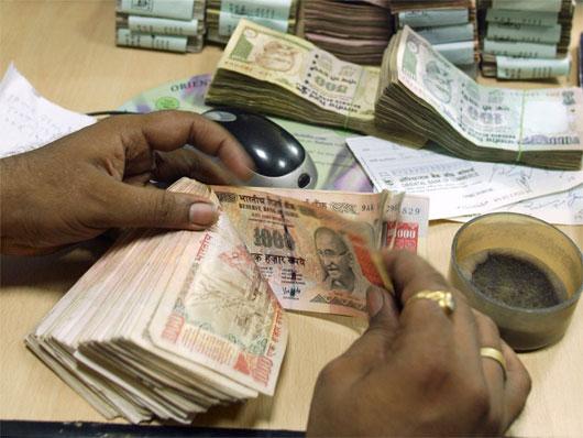 A teller counts Indian currency notes.