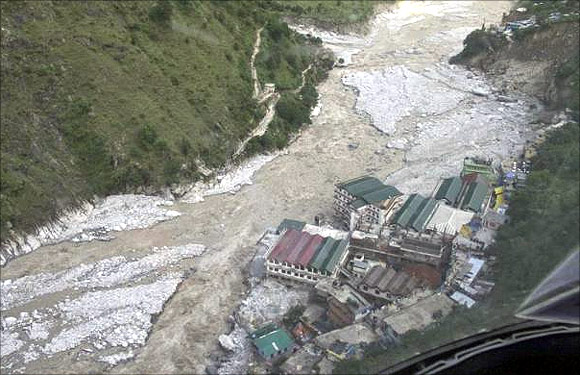 Flood waters flow next to a residential complex after heavy rains in Uttarakhand.