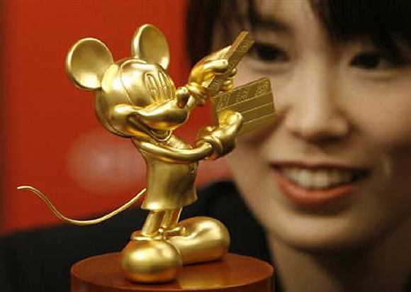 Ayako Kikuchi, an employee of jewellery maker Ginza Tanaka, poses with a statue of Mickey Mouse in Tokyo.